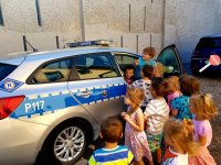Przedszkolaki oglądają policyjny radiowóz, zabawie towarzyszy ,,Sznupek&quot; maskotka śląskiej policji