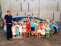 Przedszkolaki oglądają policyjny radiowóz, zabawie towarzyszy ,,Sznupek&quot; maskotka śląskiej policji