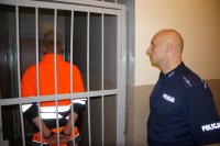 Policjant z Kuźni Raciborskiej stoi obok zatrzymanego sprawcy rozboju
