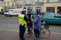 Policjanci z drogówki rozdają odblaski rowerzystce