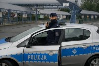 Policjant przez megafon w radiowozie ogłasza komunikat do mieszkańców związany z przestrzeganiem nakazu noszenia maseczek, zachowaniem dystansu społecznego