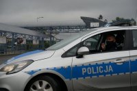 Policjant przez megafon w radiowozie ogłasza komunikat do mieszkańców związany z przestrzeganiem nakazu noszenia maseczek, zachowaniem dystansu społecznego